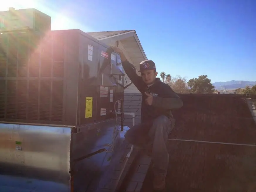 HVAC technician performing AC Tune-Up on a rooftop unit in Taft